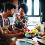 Beautiful young couple having fun and laughing while cooking in kitchen